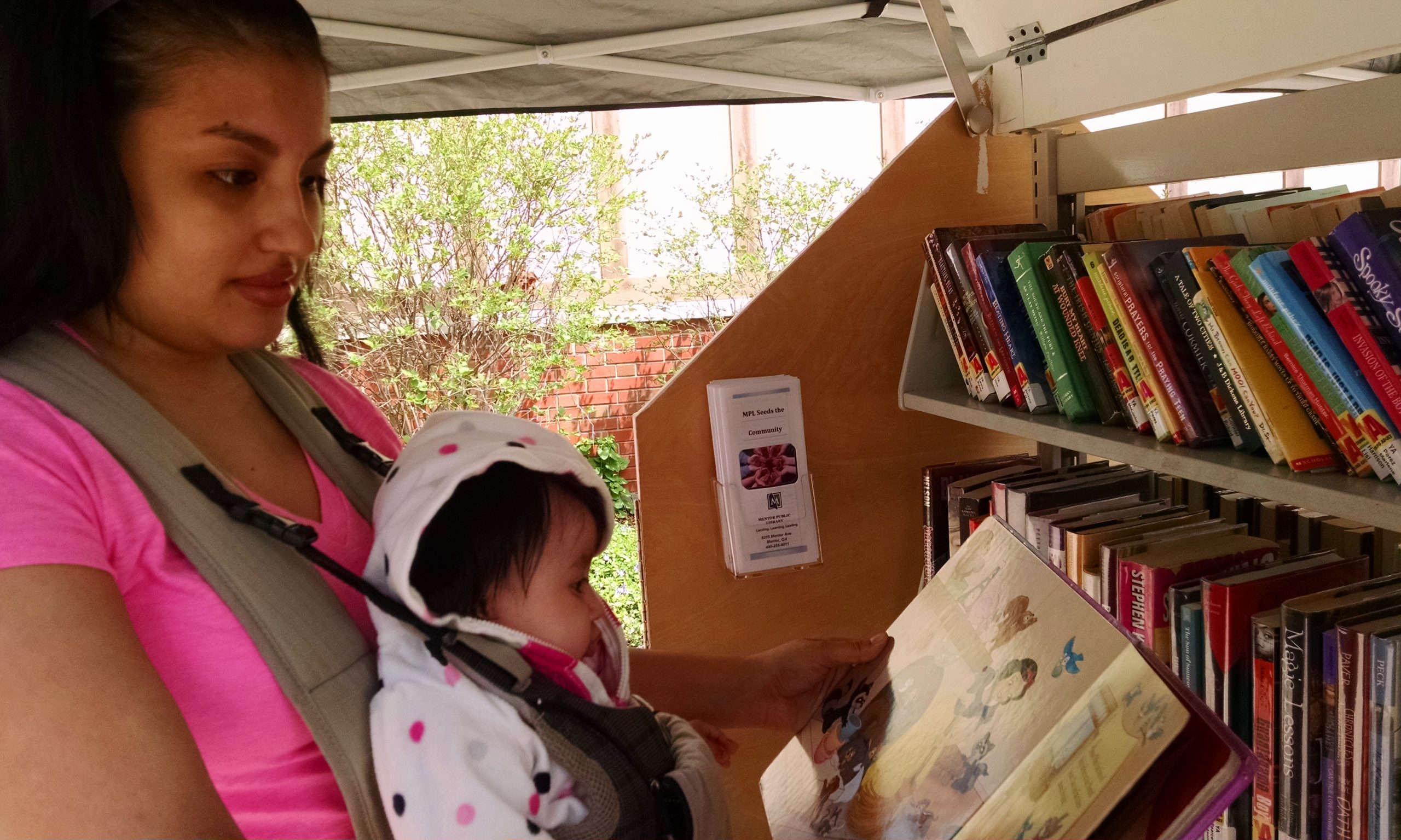 Catalea and her mother enjoy an impromptu story time by the Pop-Up Library during an Earth Day Celebration at Wildwood Cultural Center in Mentor