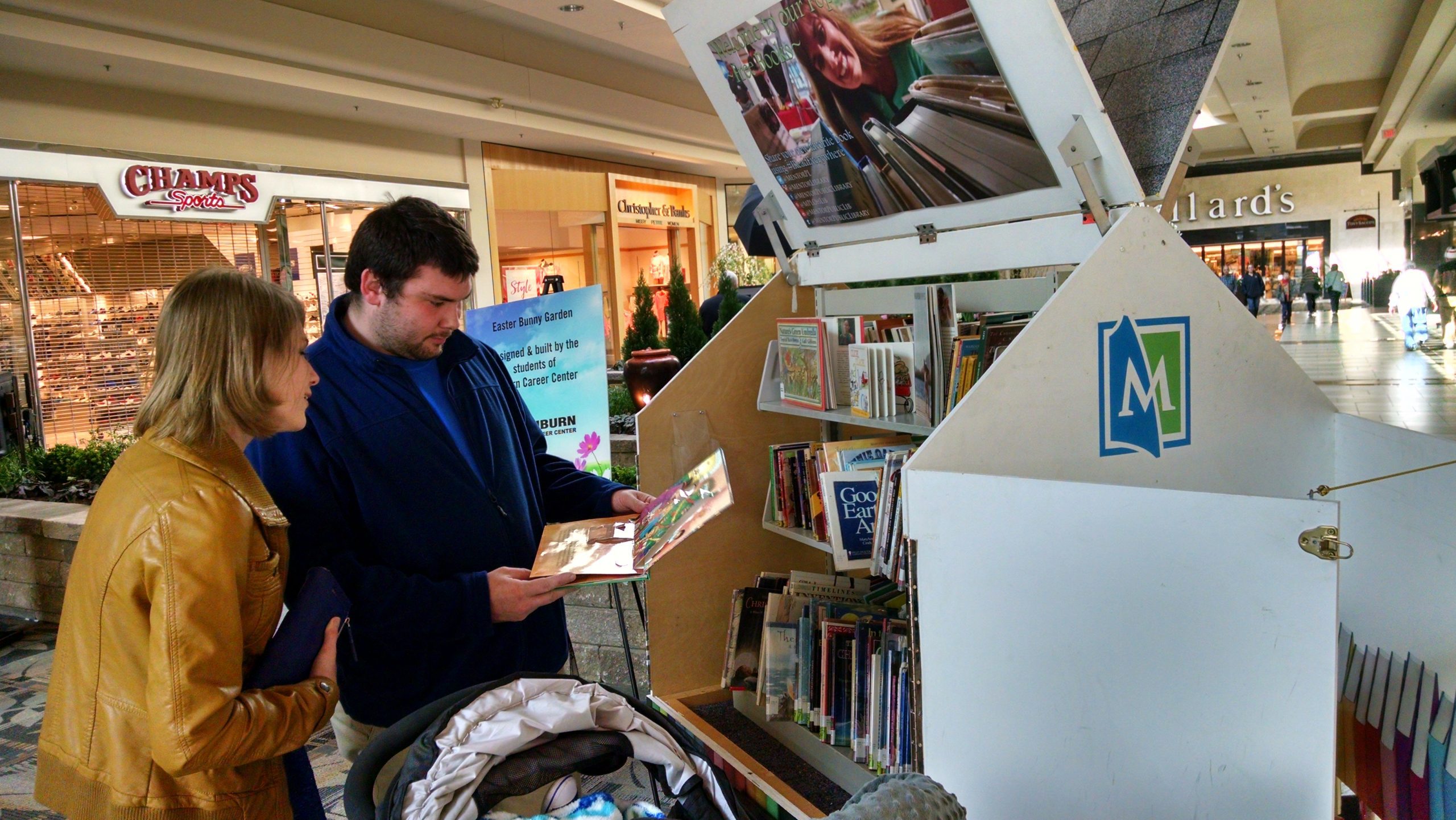 A family glances at the books in the Pop-Up Library while shopping at Great Lakes Mall.